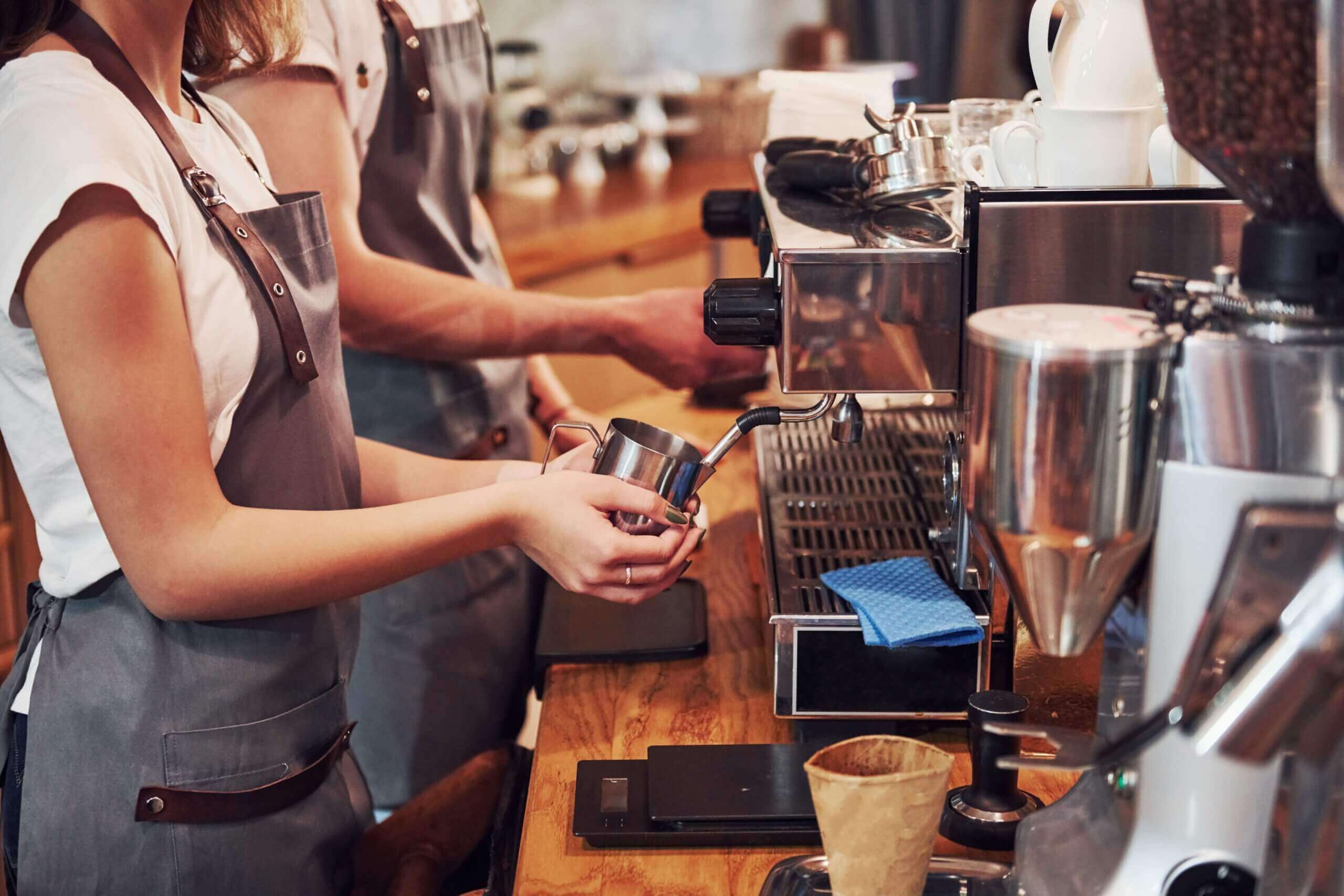 A group of baristas preparing coffee using espresso machines in a bustling coffee shop
