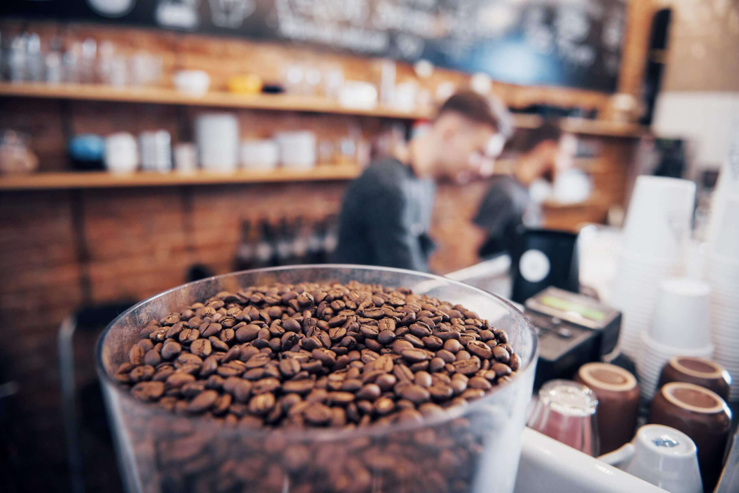 A jar of fresh coffee beans displayed on a counter in a cozy coffee shop